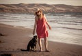 Happy attractive mature woman with her pet walking on friendly dog beach at sunset Royalty Free Stock Photo