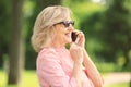 Beautiful mature woman talking on mobile phone outdoors Royalty Free Stock Photo