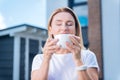 Beautiful mature woman tasting delicious morning cappuccino standing outside
