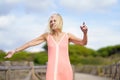 Beautiful mature woman walking along a wooden path near the beach., wearing a nice orange dress. Royalty Free Stock Photo