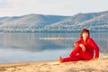 Beautiful mature women sits on a sandy beach on the background of the Volga river and the Zhiguli mountains Royalty Free Stock Photo