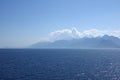 Beautiful sea landscape in soft colors with calm sea and high mountains covered with light haze on horizon