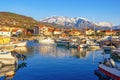 Beautiful Mediterranean landscape on sunny winter day. Fishing boats in harbor and snow-capped mountains. Montenegro, Tivat city Royalty Free Stock Photo