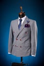 Beautiful men`s grey jacket suit with shirt and tie on a dummy or mannequin on blue background Royalty Free Stock Photo