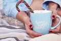 Beautiful Merry Christmas morning woman drink sweet hot cup cacao marshmallow eat lollipop candy cane wear home knitted wool sock