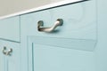 Beautiful metallic modern handle on a blue furniture facade. Close-up, selective focus