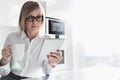 Beautiful mid adult businesswoman having coffee while using table PC at home