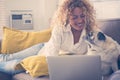 Beautiful middle age adult caucasian woman work on laptop computer while her lovely old funny pug dog look at her with love - Royalty Free Stock Photo