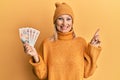 Beautiful middle age blonde woman holding 10 united kingdom pounds banknotes smiling happy pointing with hand and finger to the