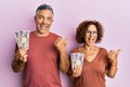 Beautiful middle age couple holding 5000 japanese yen banknotes pointing thumb up to the side smiling happy with open mouth Royalty Free Stock Photo