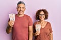 Beautiful middle age couple holding 10 united kingdom pounds banknotes looking positive and happy standing and smiling with a