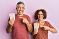 Beautiful middle age couple holding 10 united kingdom pounds banknotes smiling happy pointing with hand and finger