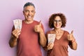 Beautiful middle age couple holding 10 united kingdom pounds banknotes smiling happy and positive, thumb up doing excellent and