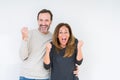 Beautiful middle age couple in love over isolated background celebrating surprised and amazed for success with arms raised and