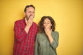 Beautiful middle age couple over isolated yellow background bored yawning tired covering mouth with hand Royalty Free Stock Photo