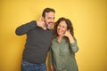 Beautiful middle age couple over isolated yellow background smiling doing phone gesture with hand and fingers like talking on the Royalty Free Stock Photo