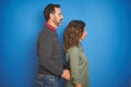 Beautiful middle age couple together standing over isolated blue background looking to side, relax profile pose with natural face Royalty Free Stock Photo