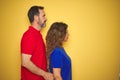 Beautiful middle age couple together standing over isolated yellow background looking to side, relax profile pose with natural Royalty Free Stock Photo