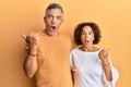 Beautiful middle age couple together wearing casual clothes surprised pointing with hand finger to the side, open mouth amazed Royalty Free Stock Photo