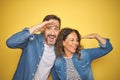 Beautiful middle age couple together wearing denim shirt over isolated yellow background very happy and smiling looking far away Royalty Free Stock Photo