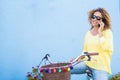 Beautiful middle age healthy young woman do a phone call sit down on a vintage coloured happy bike and blue background wall -