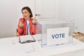 Beautiful middle age hispanic woman at political election sitting by ballot doing money gesture with hands, asking for salary