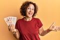 Beautiful middle age mature woman holding 10 united kingdom pounds banknotes celebrating achievement with happy smile and winner