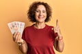Beautiful middle age mature woman holding 10 united kingdom pounds banknotes smiling with an idea or question pointing finger with