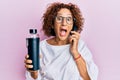 Beautiful middle age mature woman using smartphone holding water bottle celebrating crazy and amazed for success with open eyes Royalty Free Stock Photo