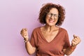 Beautiful middle age mature woman wearing casual clothes and glasses very happy and excited doing winner gesture with arms raised, Royalty Free Stock Photo