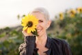 Beautiful middle age woman in a rural field scene outdoors standing between sunflowers