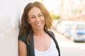 Beautiful middle age woman smiling cheerful leaning on a brick wall at the city street on a sunny day Royalty Free Stock Photo