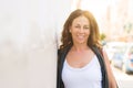 Beautiful middle age woman smiling cheerful leaning on a brick wall at the city street on a sunny day Royalty Free Stock Photo