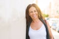 Beautiful middle age woman smiling cheerful leaning on a brick wall at the city street on a sunny day Royalty Free Stock Photo