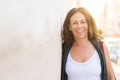 Beautiful middle age woman smiling cheerful leaning on a brick wall at the city street on a sunny day Royalty Free Stock Photo