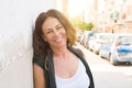 Beautiful middle age woman smiling cheerful leaning on a brick wall at the city street on a sunny day Royalty Free Stock Photo