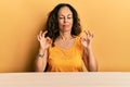 Beautiful middle age woman wearing casual clothes sitting on the table relaxed and smiling with eyes closed doing meditation Royalty Free Stock Photo