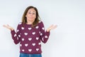 Beautiful middle age woman wearing heart sweater over isolated background clueless and confused expression with arms and hands Royalty Free Stock Photo