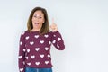 Beautiful middle age woman wearing heart sweater over isolated background pointing finger up with successful idea