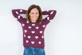 Beautiful middle age woman wearing heart sweater over isolated background Relaxing and stretching with arms and hands behind head Royalty Free Stock Photo