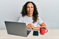 Beautiful middle age woman working at the office using computer laptop with serious expression on face Royalty Free Stock Photo