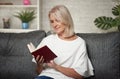 Beautiful middle aged blonde woman is reading a book at home Royalty Free Stock Photo