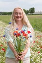 beautiful middle-aged blonde woman stands among a flowering field of poppies Royalty Free Stock Photo