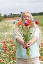 beautiful middle-aged blonde woman stands among a flowering field of poppies Royalty Free Stock Photo