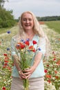 beautiful middle-aged blonde woman stands among a flowering field of poppies Royalty Free Stock Photo