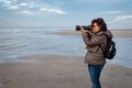 Beautiful middle-aged woman with glasses taking photos with a DSLR camera on the beach Royalty Free Stock Photo