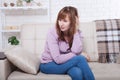 Beautiful middle aged brunette woman holding head depressed on sofa. Home background. Menopause time Royalty Free Stock Photo