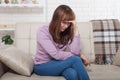 Sad middle aged woman sitting on sofa and crying. Home background. Copy space and mock up Royalty Free Stock Photo