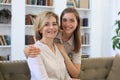 Beautiful middle aged mom and her adult daughter are hugging, looking at camera and smiling Royalty Free Stock Photo