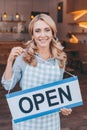 beautiful middle aged waitress in apron holding sign open and smiling Royalty Free Stock Photo